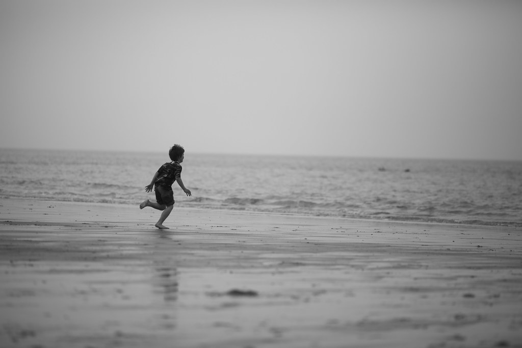 A young boy running on a beach.